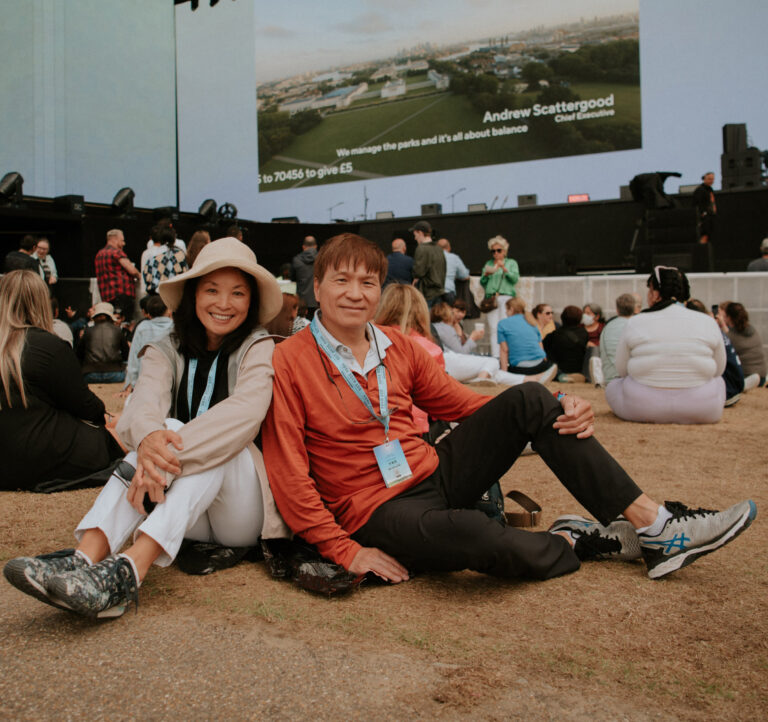 Two fans sitting in front of the Great Oak Stage at BST Hyde Park